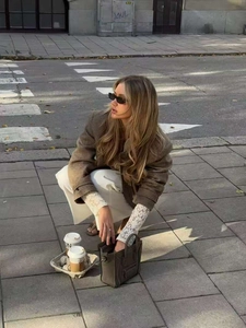 Vista street style di una borsa grigia abbinata a un blazer di lana marrone e pantaloni