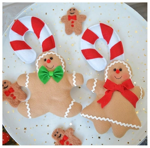 Close-up of gingerbread man and candy cane felt ornaments on a white festive tray