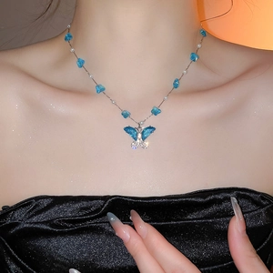 Detalle de collar de mariposa con colgante azul, perlas y brillantes diamantes de imitación