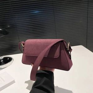 Detail of wine red suede shoulder bag with elegant wide strap and gold hardware