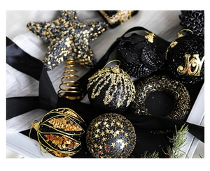 Close-up of black and gold Christmas ornaments with sequins and star tree topper