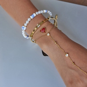 Close-up of gold cherry bangle and layered pearl bracelet set on female wrist