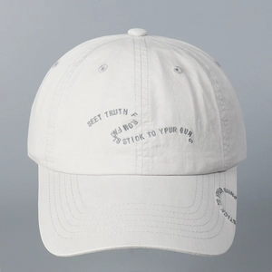 Detail of white cotton baseball cap showing gray embroidered English letters and stitching