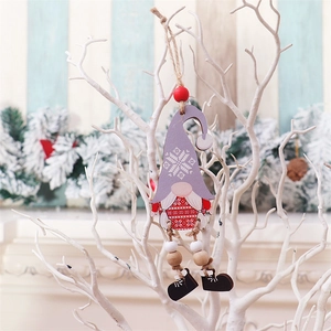 Detail of wooden gnome ornament with purple snowflake hat and red sweater on white branches