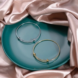 Detail of adjustable gold and silver metal bangles on elegant green tray and pink satin