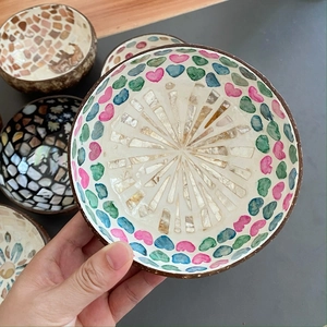 Decorative coconut shell bowl with shell inlay and colorful heart patterns shown in hand