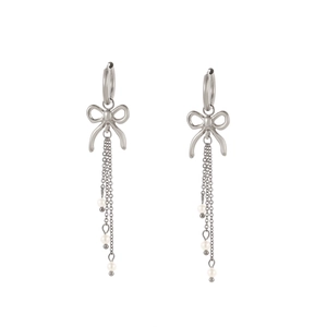 Détail de boucles d'oreilles nœud argenté avec chaînes à pompons et perles blanches