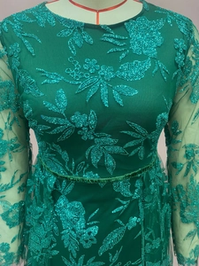 Detailed view of emerald green lace dress with intricate sequin floral embroidery