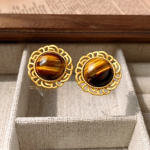 Detailed close-up of tiger eye stud earrings in vintage gold filigree setting