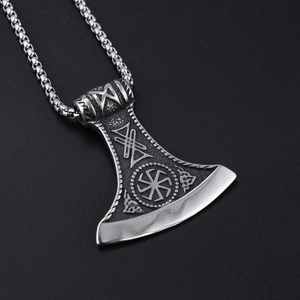 Macro view of vintage silver Axe of Perun pendant with intricate runes on black texture