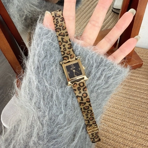 Close-up of golden H-shaped watch case with starry dial and leopard print metal strap
