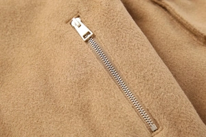 Detailed macro view of high-quality gold metal zipper on camel wool jacket fabric