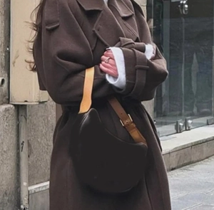 Détail d'un sac selle vintage marron foncé avec rabat et bandoulière réglable