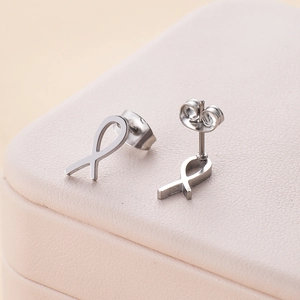 Boucles d'oreilles nœud en acier inoxydable poli sur un coffret à bijoux en cuir crème