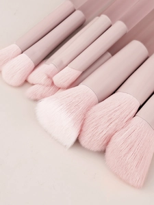 Dettaglio macro di setole sintetiche rosa morbide e manici smerigliati trasparenti dei pennelli