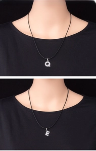 Close-up of sparkling silver alloy letter Q and E pendants with inlaid rhinestones
