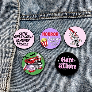 Set of five horror movie lover enamel pins displayed on blue denim jeans pocket