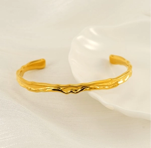 Dettaglio macro del bracciale dorato con texture martellata su piatto a conchiglia