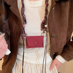 Detail of vintage red micro bag with woven silk strap worn over a corduroy jacket