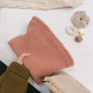 Detail view of the soft lambswool texture and metal zipper on the pink cosmetic bag