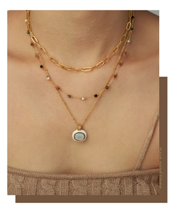 Detailed close-up of a three-layer gold necklace set with colorful beads and opal pendant