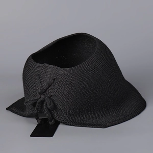 Detail of black straw visor featuring a feminine side bow and fine woven texture