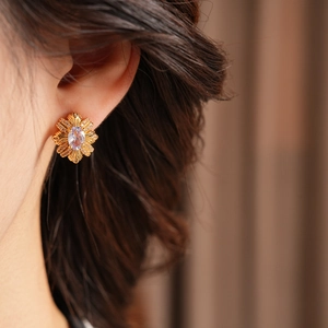 Détail de boucles d'oreilles fleur vintage en or avec gemme violette et zircons