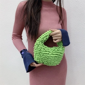 Detail of green chenille plush handbag featuring textured loop fabric and soft handle
