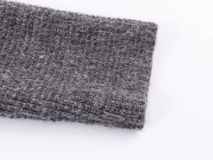 Close-up of dark grey knitted cardigan sleeve showing detailed wool texture and stitching