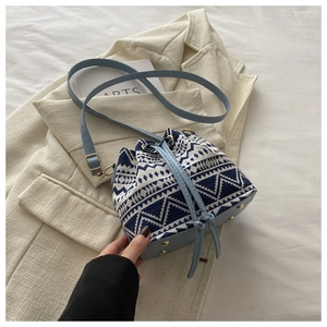 Detail of blue and beige geometric canvas bucket bag with PU leather drawstring and gold hardware