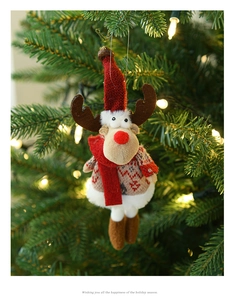 Dettaglio di una renna di peluche con maglione lavorato a maglia appesa all'albero