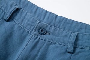 Detailed close-up of blue cotton cargo shorts waistband with button and stitching