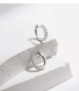 Detailed close-up of sparkling moissanite hoop earrings on elegant white stone display