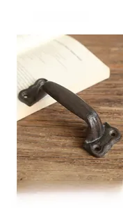 Detail of dark brown cast iron door handle with industrial texture on wooden surface