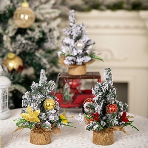 Three mini frosted Christmas trees with red and gold ornaments on rustic burlap bases