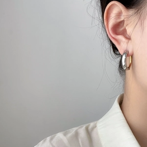 Two-tone silver and gold curved hoop earrings in stainless steel on female model