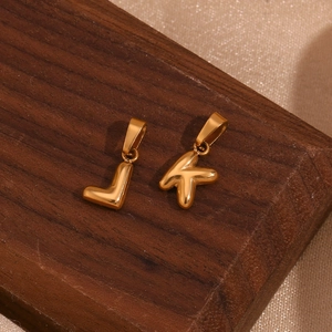 Macro shot of 18K gold plated polished bubble letter J and K pendants on wood