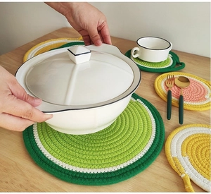 Close-up of woven cotton rope placemats and fruit-shaped coasters on a wooden table