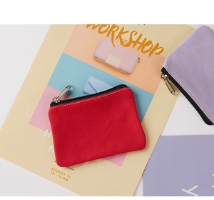 Flat lay of red and purple canvas coin purses with silver zippers on colorful backgrounds