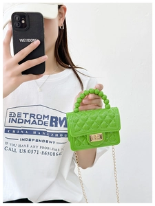 Close-up of bright green quilted PVC jelly bag with beaded handle and gold chain strap