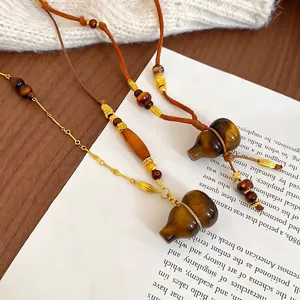 Tiger Eye Stone Gourd Necklace with gold beads on warm white knit and wood background