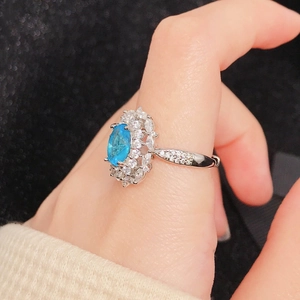 Macro shot of silver ring featuring oval blue gemstone with double-layered halo setting