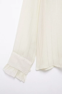 Detail of white ruffle cuffs on transparent vertical stripe texture blouse for women