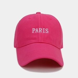 Detailed close-up of white PARIS embroidery on a pink cotton twill baseball cap