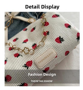 Close-up of strawberry print corduroy bag with gold floral chain and leather tag