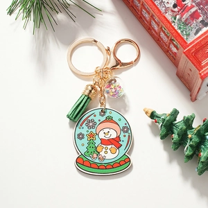 Close-up of Christmas snowman keychain with green tassel and starry crystal ball ornament