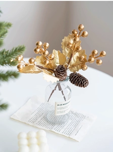 Detail of artificial golden berries and pine cones in a glass vase for home decor
