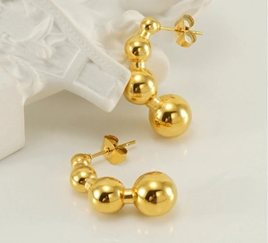 Dettaglio macro di orecchini a perno dorati 18k con sfere metalliche lucide a sfumatura