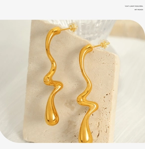 Macro view of gold twisted metal earrings with elegant wavy design and teardrop bottom