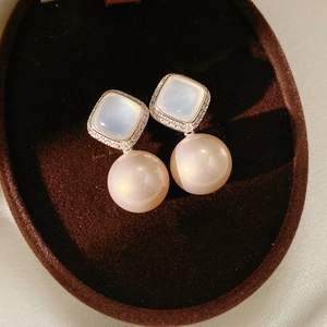 Macro shot of square zircon stud with large pink pearl earring in velvet jewelry box